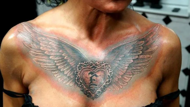 Тату сердце с крыльями на груди с буквой