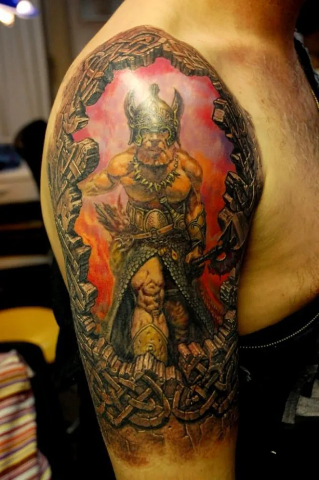 Тату викинг в шлеме со скандом в камне на плече