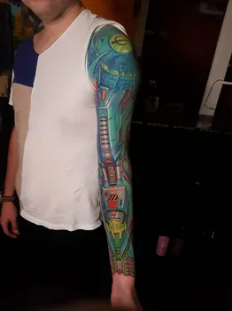 Яркая киберпанковская татуировка на руке с изображением технологичных элементов и механизмов в зеленых и синих тонах, создающая ощущение высокотехнологичной брони.