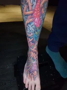 Татуировка на ноге в стиле биомеханики с переплетением металлических элементов и растительных форм, с ярким акцентом на цветок, символизирующий гармонию природы и технологий.