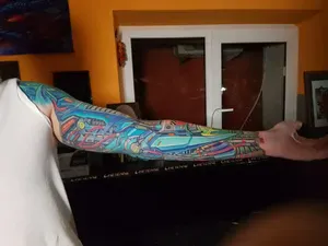 Татуировка на руке в стиле киберпанк с яркими синими и красными акцентами, изображающая сложные механические элементы и технологичные конструкции.